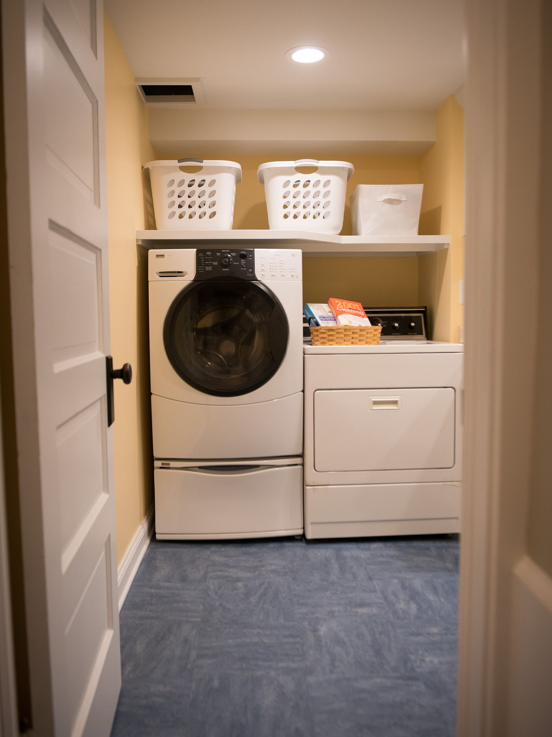 washing machine and dryer with open shelving above in the basement