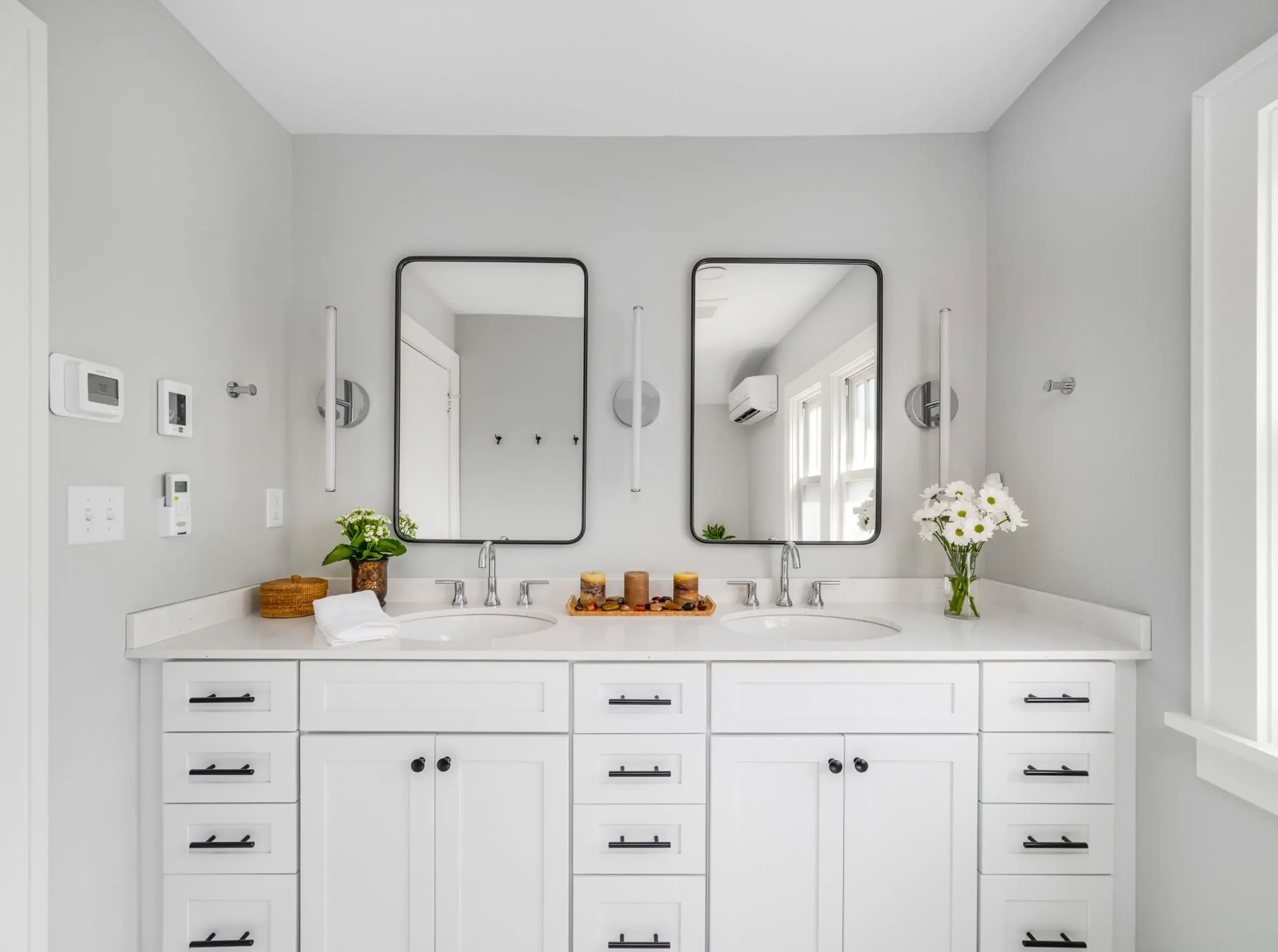 white bathroom with a double vanity top and candles and florals ready for holiday guests