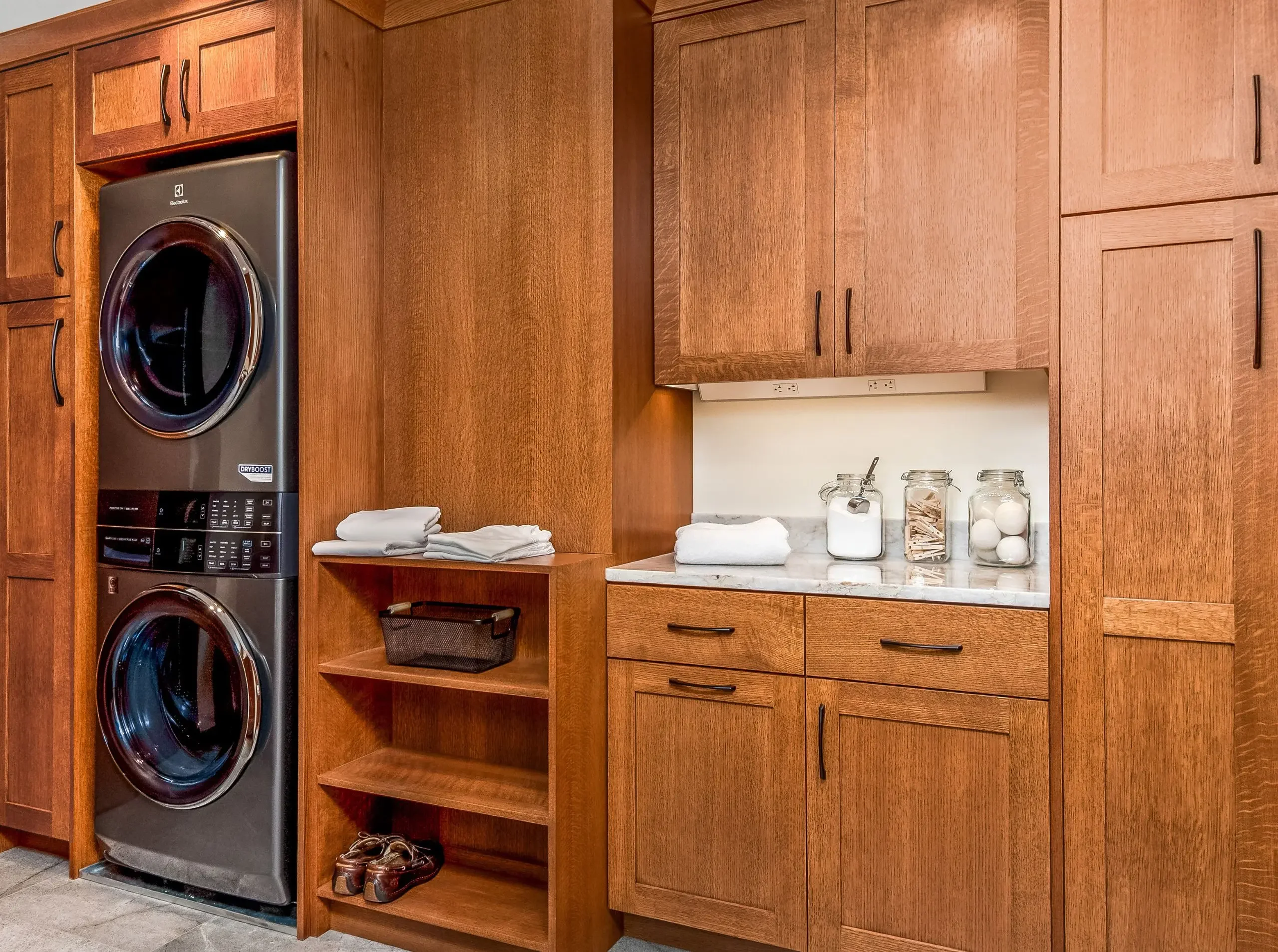laundry room with stacked laundry and open shelving with linens
