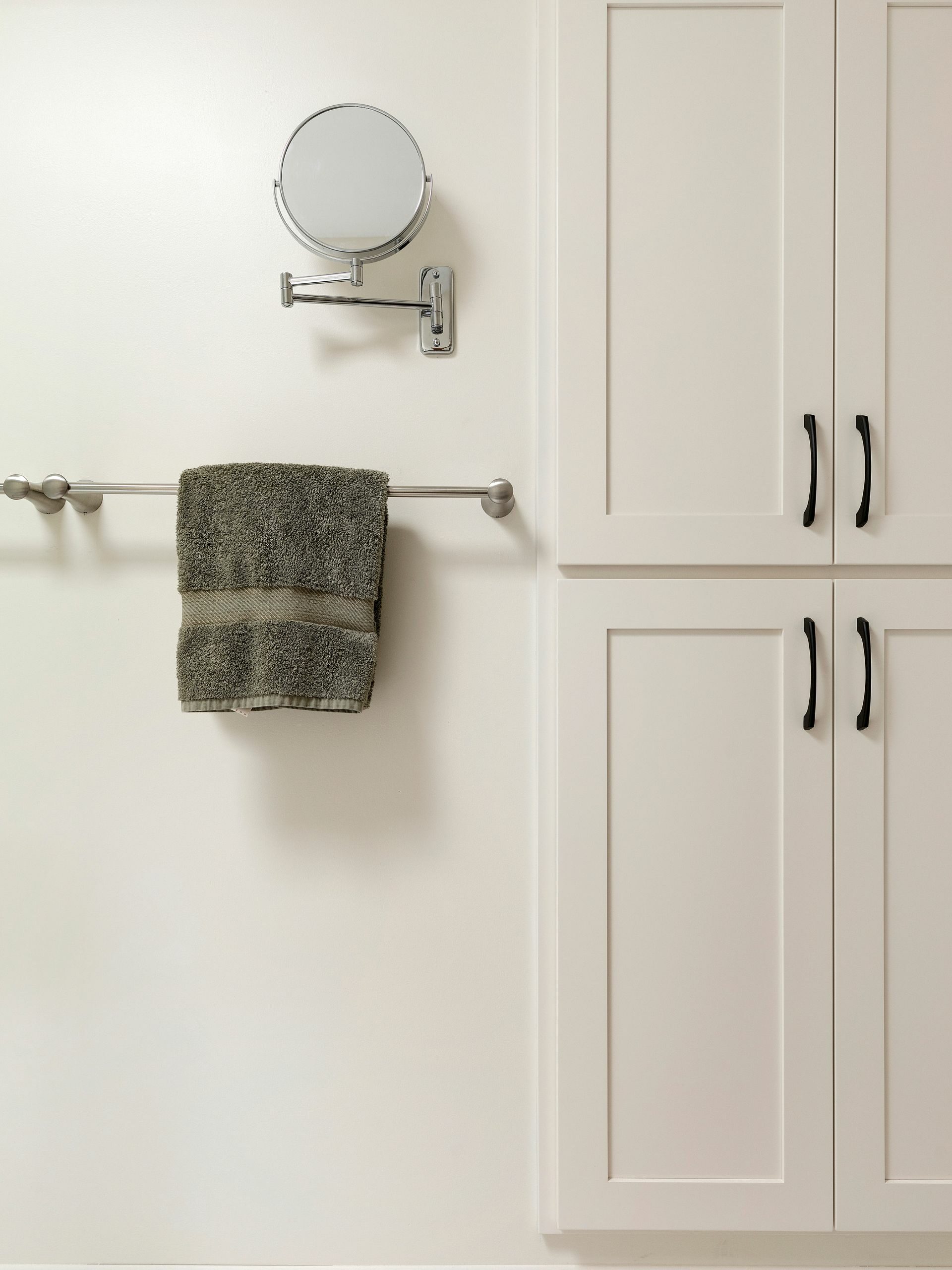 white linen closet doors and a towel and mirror mounted to the wall