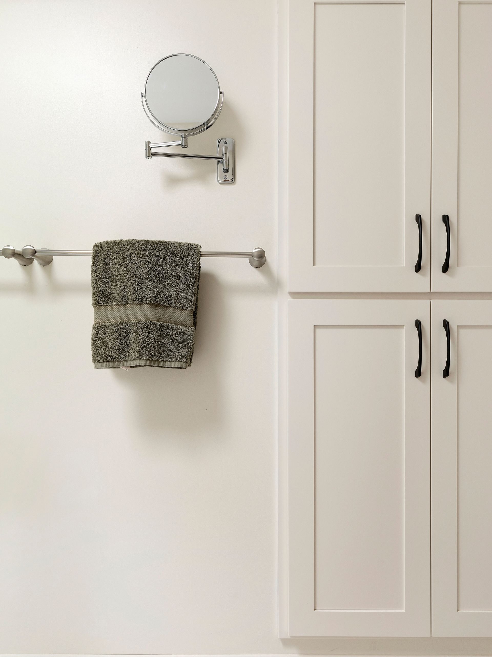 white cabinets flush with the wall, mirror and towel rack