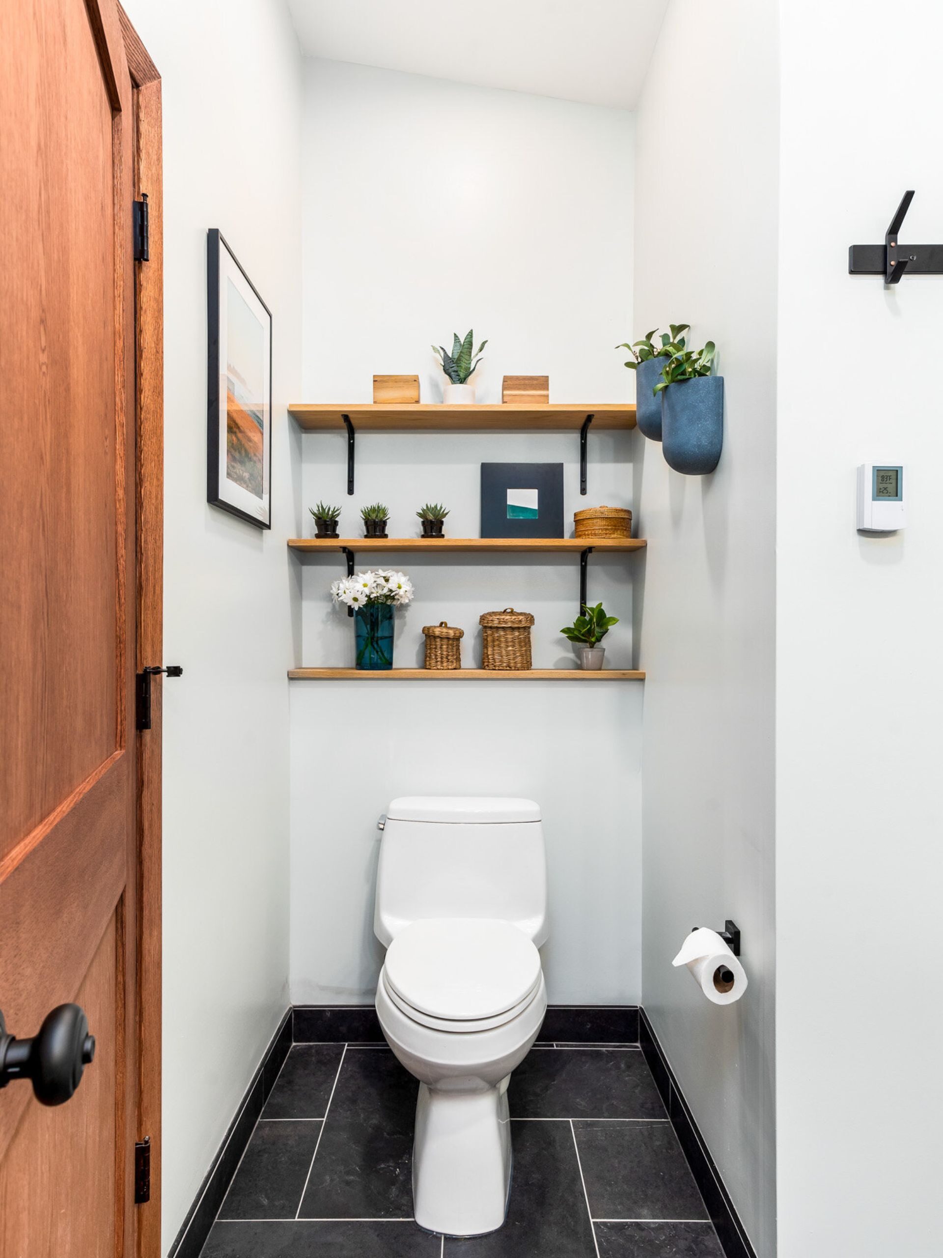 toilet with display shelves with decor above