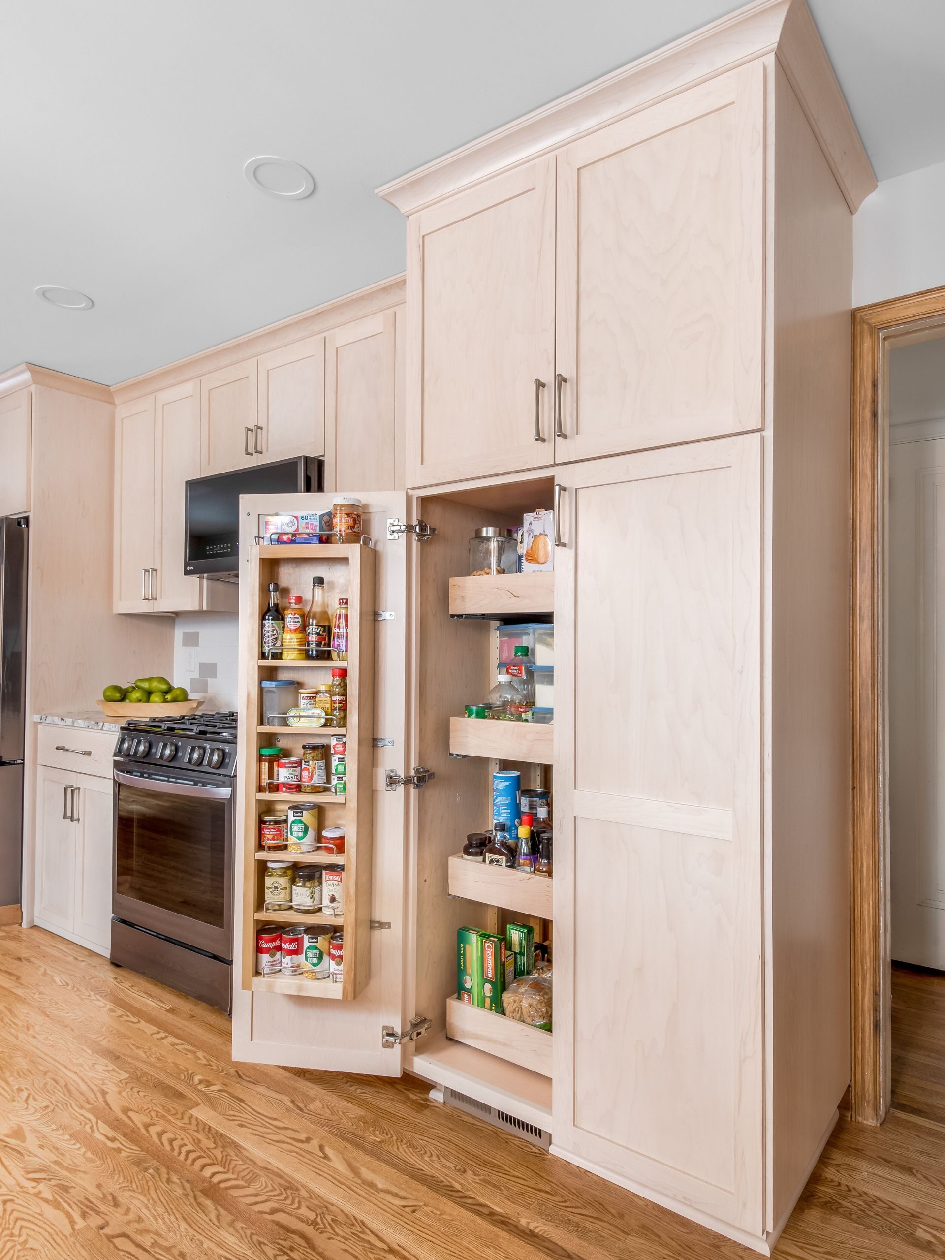 light maple stain cabinetry with pantry door open displaying pull out shelves and spice rack