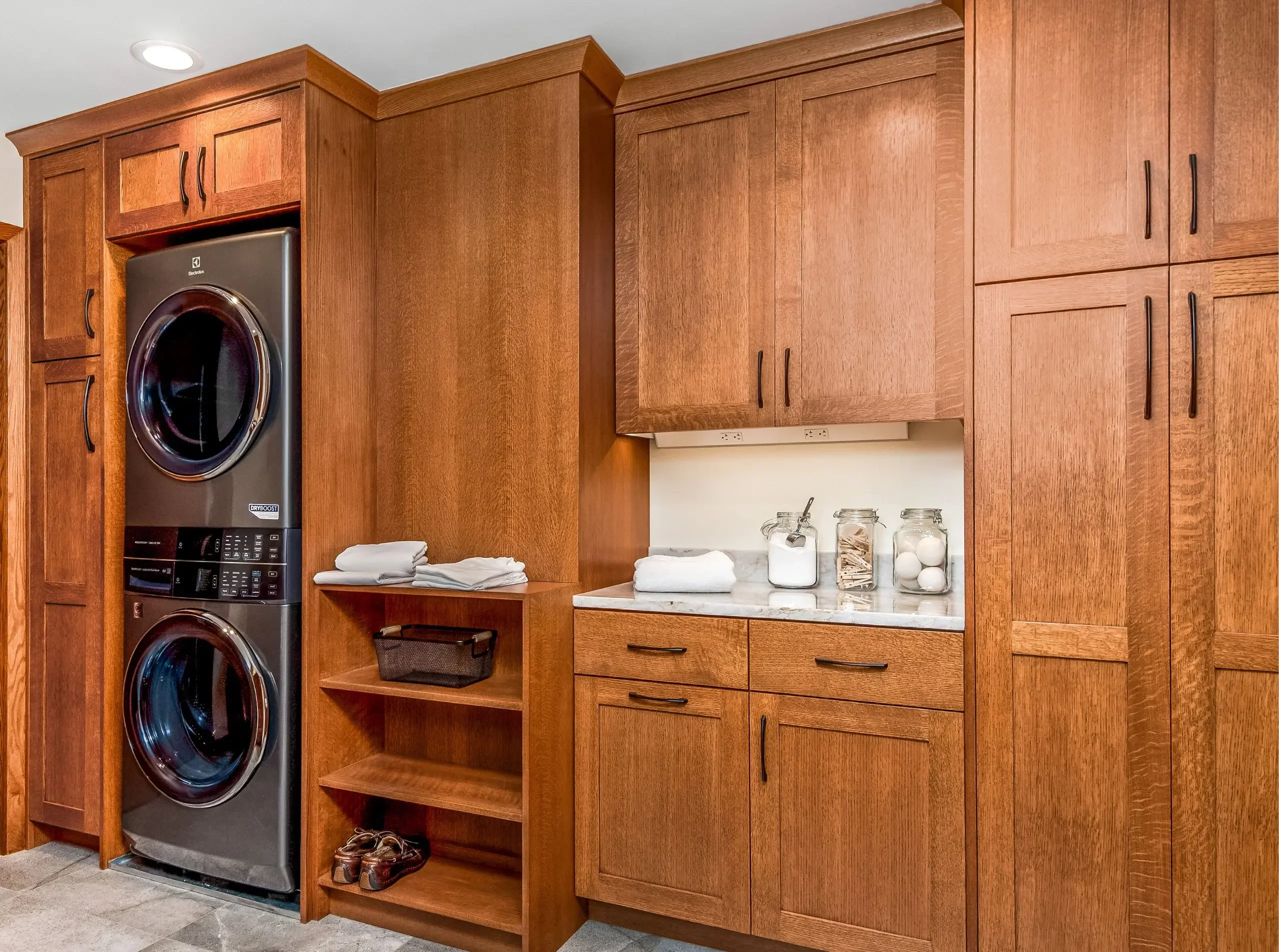 laundry room with stacked laundry and quarter-sawn oak cabinetry