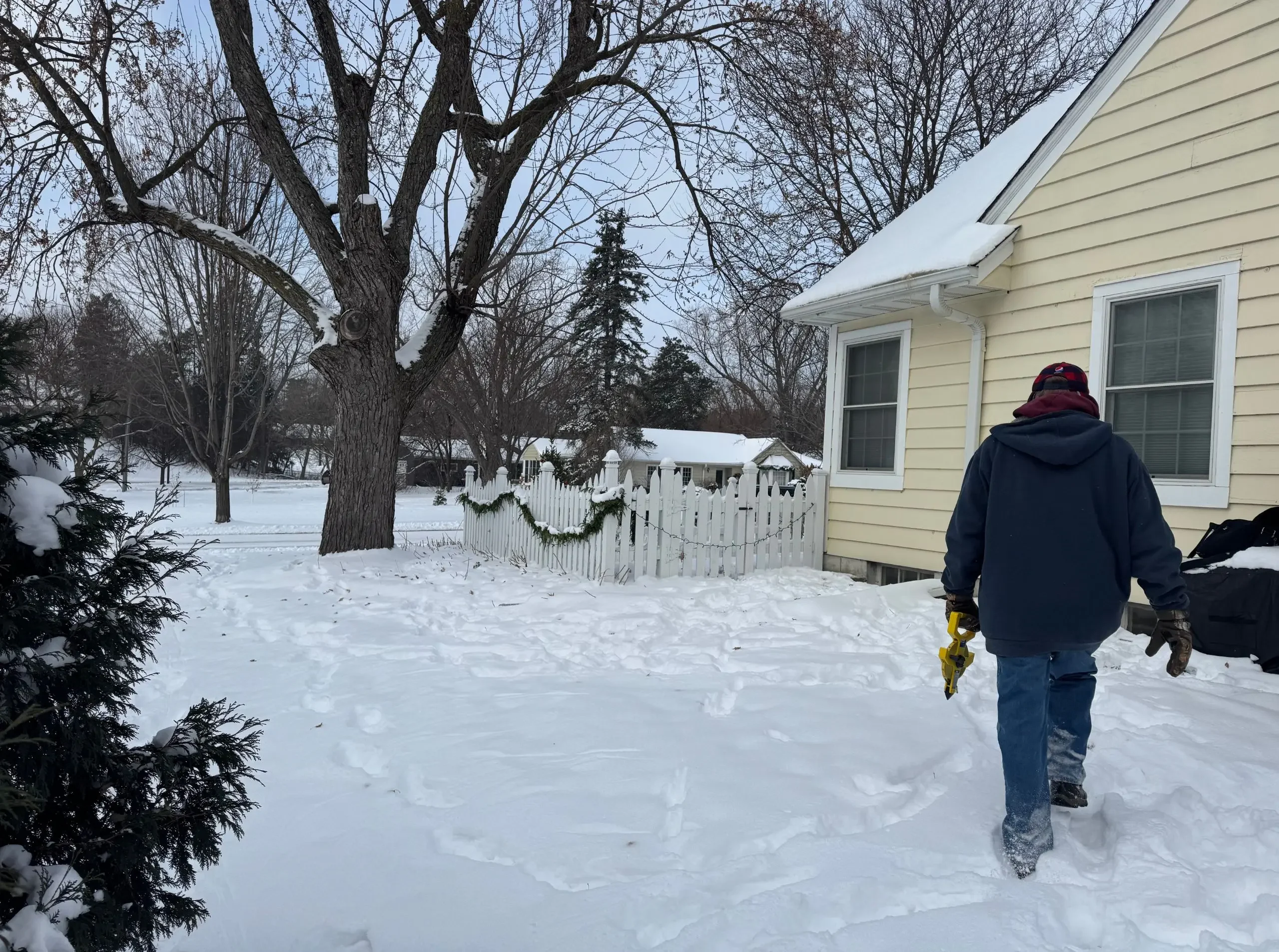 contractor walking in deep snow in Minneapolis measuring property line for a new addition
